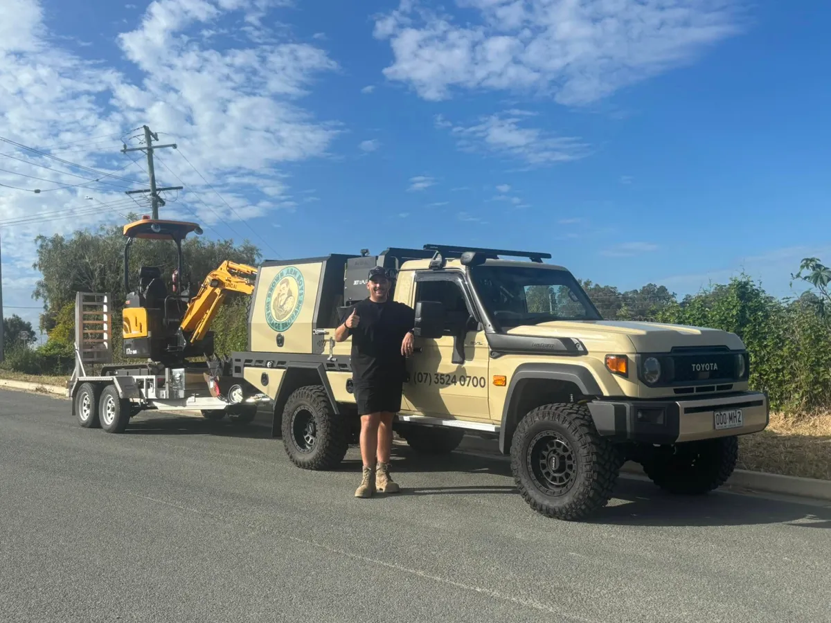 Brown Arm Boys Drainage Brisbane drainer beside the branded work ute towing a mini excavator