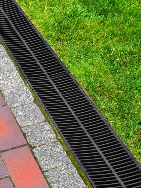 Channel drain installation between a lawn and paved path in Brisbane