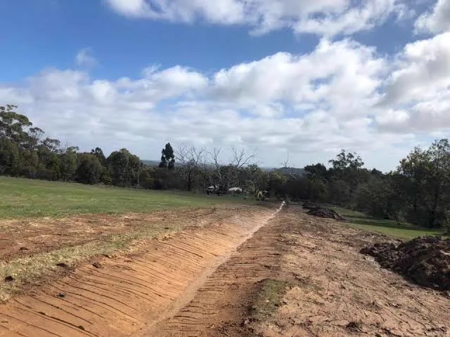 Freshly shaped earth spoon drain during a spoon drain installation in Brisbane